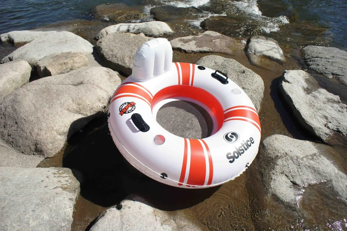 A playful scene of an inflatable tube floating on the river near a rocky shoreline, suggesting opportunities for swimming, floating, and water-based fun just steps from the cabin.
